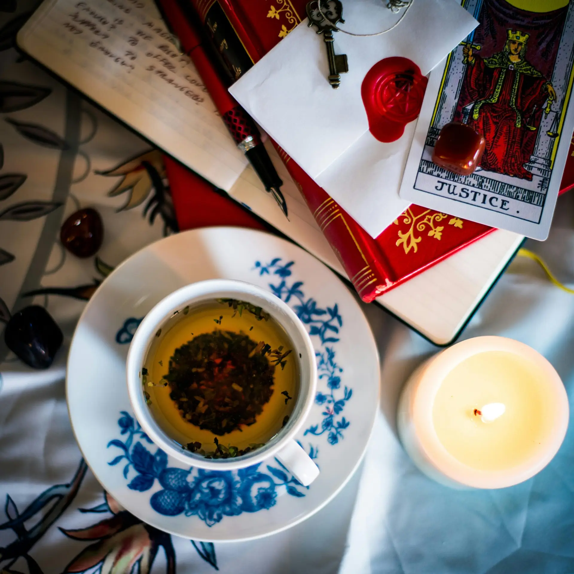 A cozy setup of tea, tarot cards, and candlelight creates a mystical ambiance.