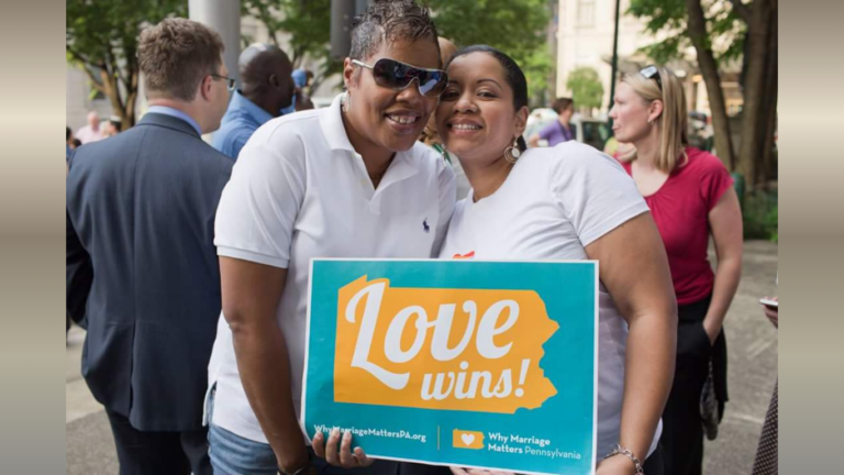 Mel and Vinnie Morris 2 african american women standing in crowd with Love Wins sign