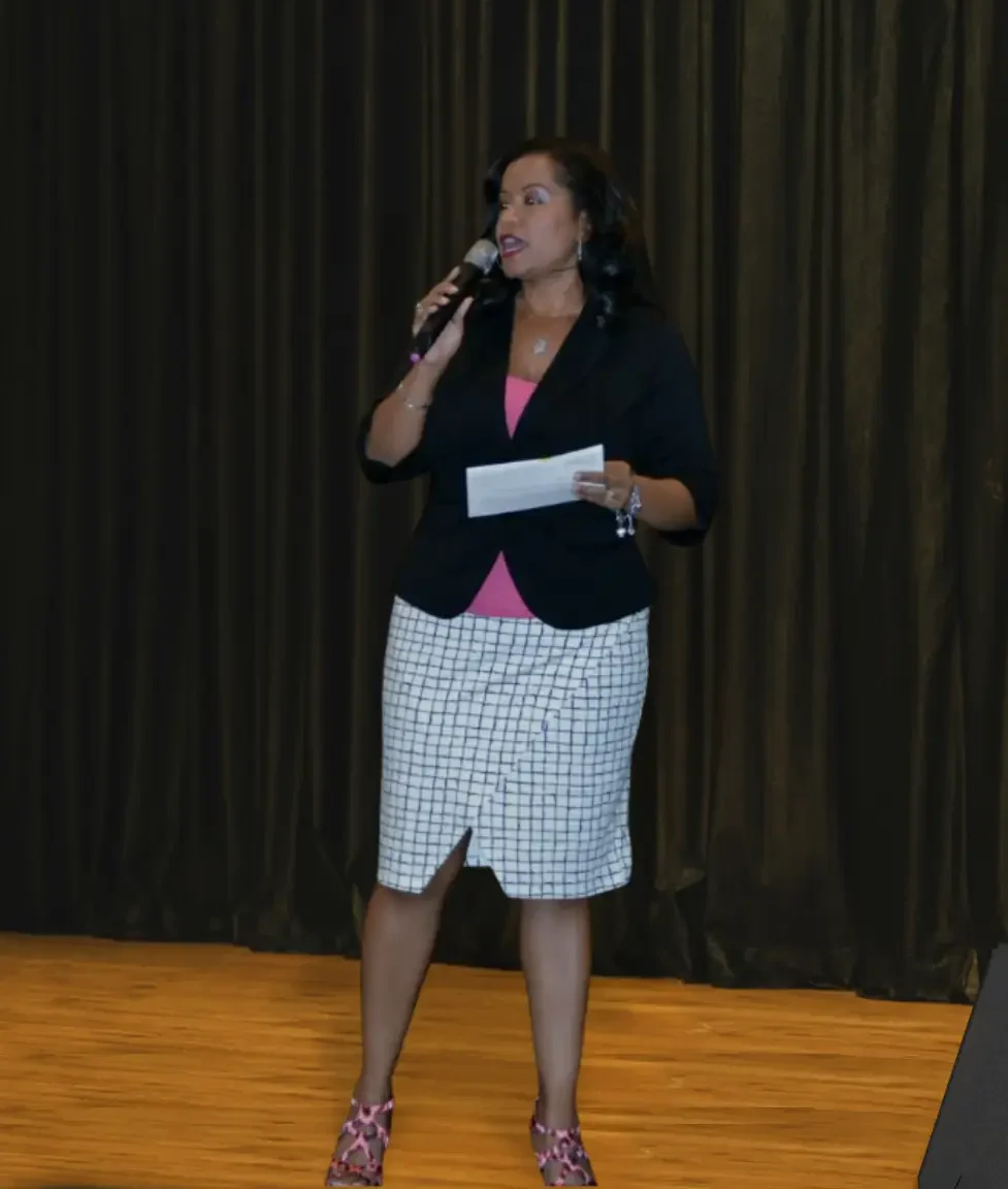 african american woman standing on a stage holding a microphone speaking