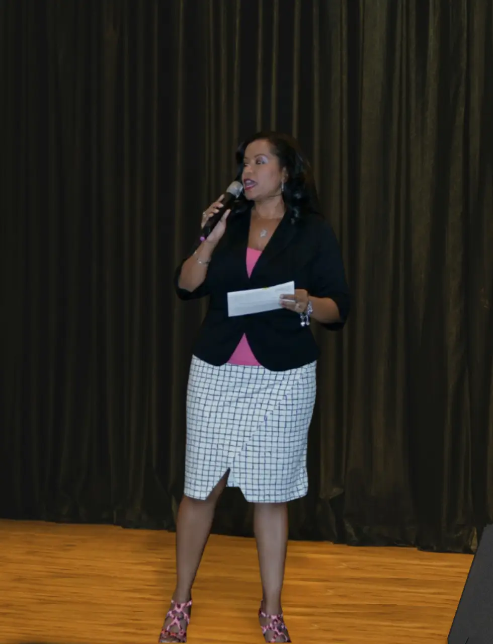 african american woman standing on a stage holding a microphone speaking